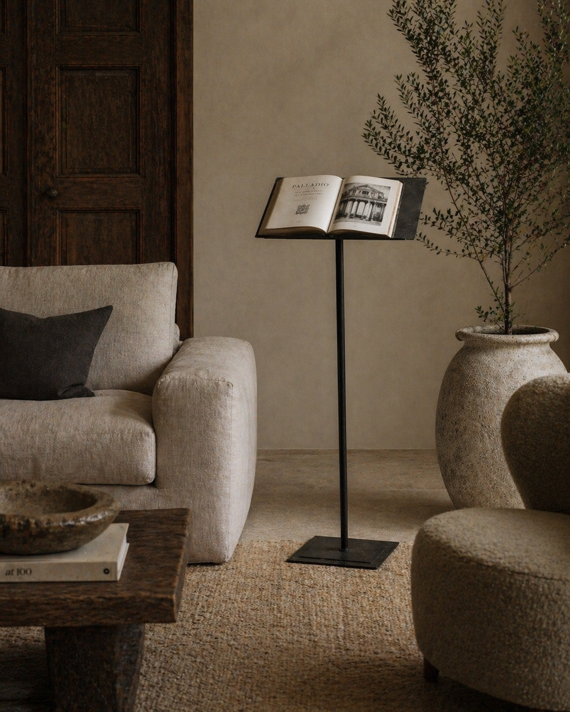 Cozy living room with a beige armchair, wooden coffee table, and book open as decor on forged Italian iron antique lectern