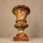 Rustic, ornate urn against a beige background. French small antique urn. 