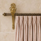 Decorative French Antique gilt curtain bracket with pink blush velvet curtains with ornate finial against a beige wall