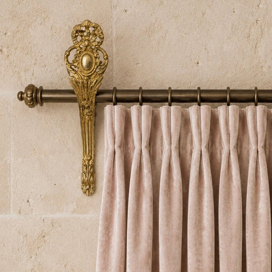 Decorative French Antique gilt curtain bracket with pink blush velvet curtains with ornate finial against a beige wall