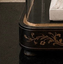 Decorative black and gold piece of furniture with intricate designs on a dark surface. dome on a wooden surface. Antique French glass dome large oval