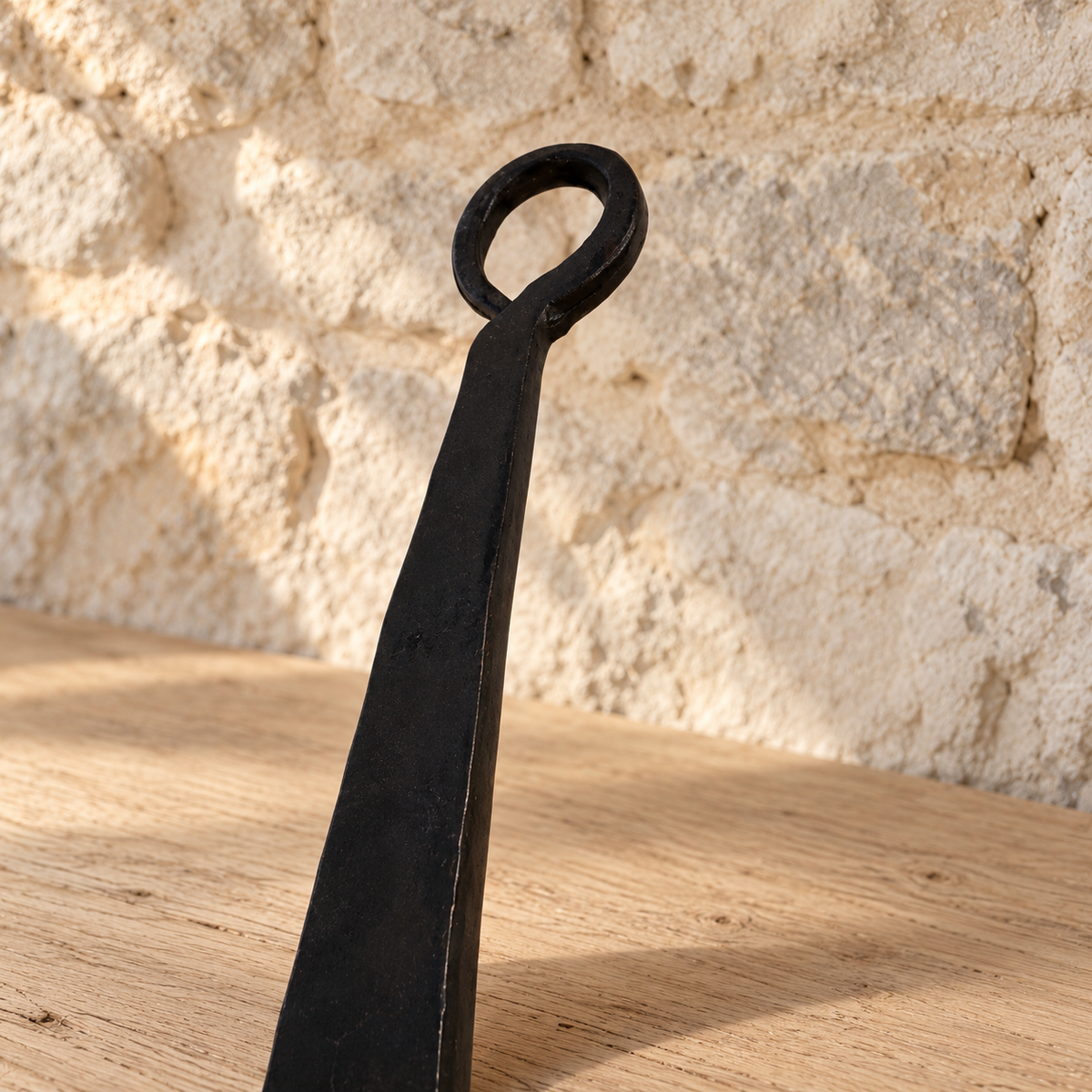 Curled hanging loop at the end of the ladle’s dark iron handle