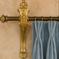 Decorative antique french gold curtain rod  bracketwith intricate design against a beige wall with blue curtains.