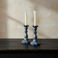 Two blue and white ceramic candle holders with candles on a wooden surface.