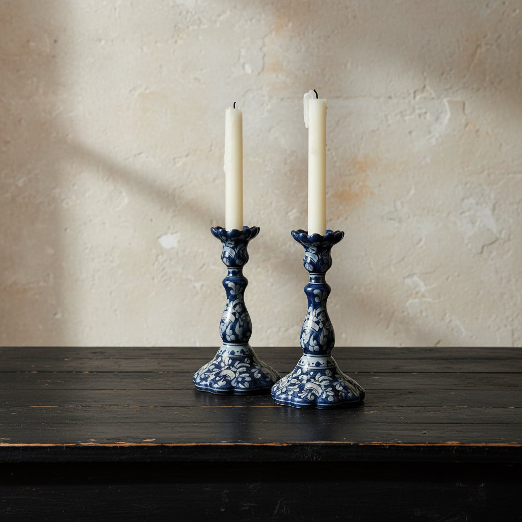 Two blue and white ceramic candle holders with candles on a wooden surface.