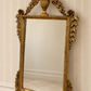 Italian giltwood mirror with urn crest, carved foliage and scroll feet