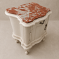 White ornate cabinet with a red marble top on a beige background Italian marble bedside tables with red marble.  