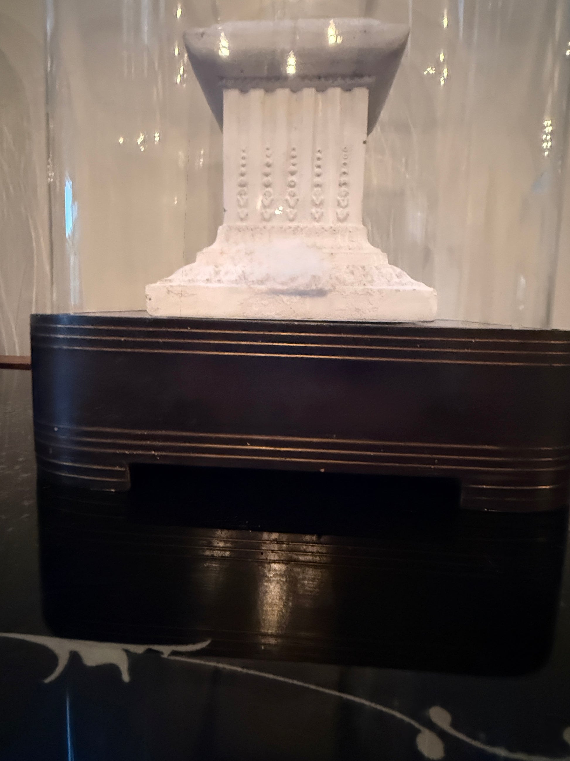 Decorative white column on a black base with a blurred background antique French cloche base 