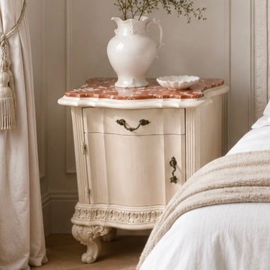 Vintage-style nightstand with marble top and white pitcher on a neutral bedroom wall. Italian marble bedside tables with red marble.  