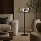 Cozy living room with a beige armchair, wooden coffee table, and book open as decor on forged Italian iron antique lectern 