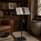 Open book on a forged Italian iron antique lectern  in a cozy room with books and a plant