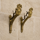 Pair of ornate brass French ANtique gilt curtain rod brackets wall brackets on a limestone stone wall.